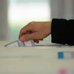 Un elettore che inserisce la scheda in un'urna elettorale